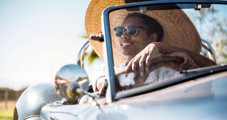 Woman driving a vintage car in summer.